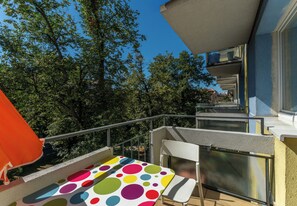 A balcony with a colorful polka dot tablecloth, a white chair, and a metal railing. - Retoryka Old Town Colorful Studio (Kraków)