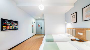A hotel room with two beds, a flat-screen TV mounted on the wall, and a wooden headboard.