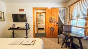 A hotel room with a bed, a desk with a coffee machine, a television, and a door labeled 'LAVENDER.' - Sweet Pecos  Gruene Cottages (New Braunfels)
