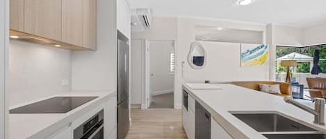 A modern kitchen with white cabinetry, a central island with a sink, and a view to a dining area.