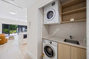 Et moderne køkken med indbyggede hårde hvidevarer, en vask og et vindue med udsigt til en have.