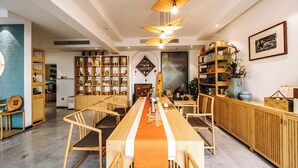 A spacious dining area with a long table, wooden chairs, and a central decorative element. - The Tea & Bamboo Retreat (Hangzhou)