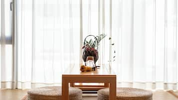Una habitació amb taula de fusta, otomans de veta i un arranjament de plantes.