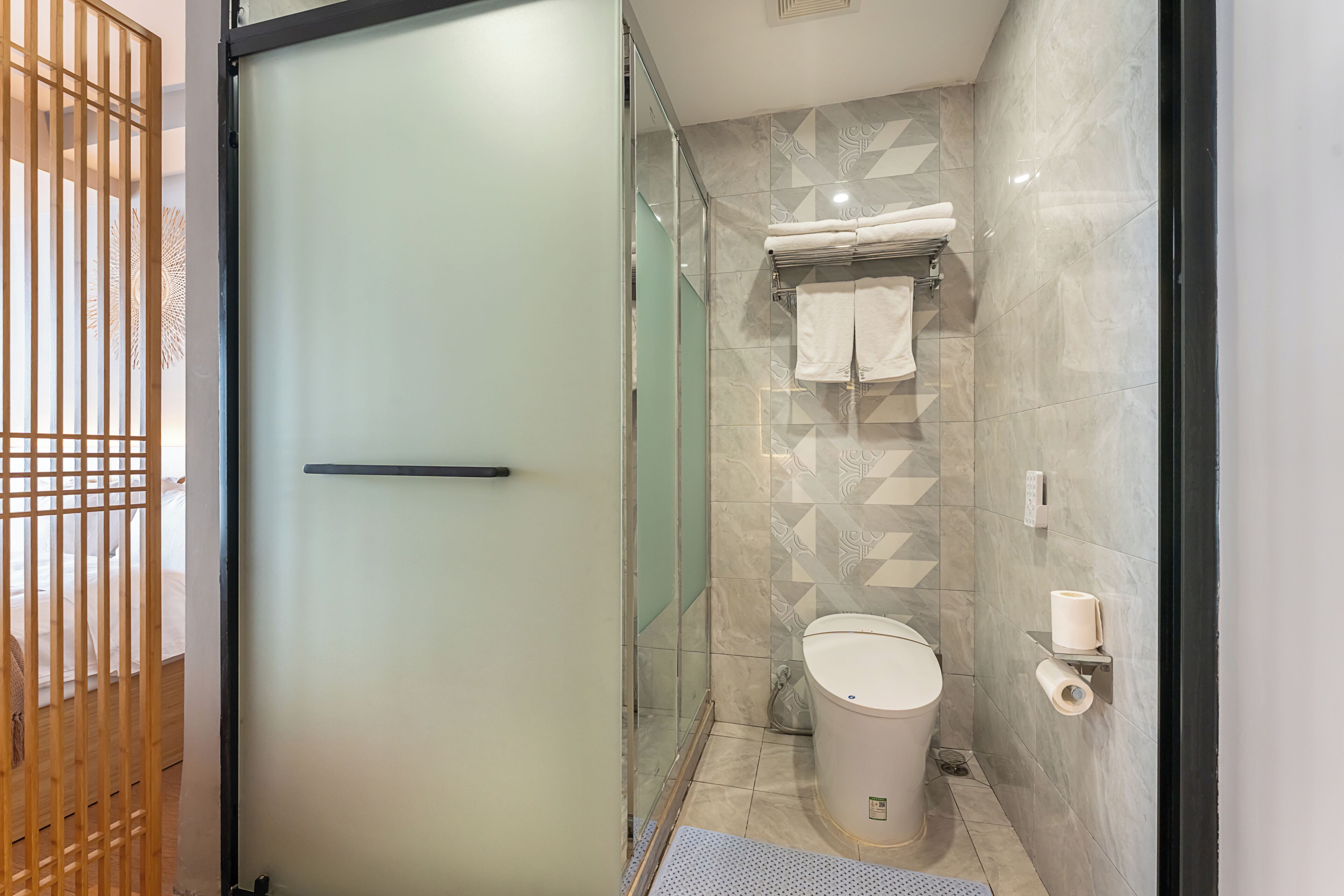 Un baño moderno con cabina de ducha de vidrio, inodoro y toallero.