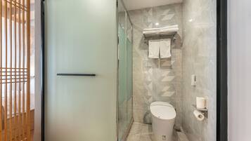 Un baño moderno con cabina de ducha de vidrio, inodoro y toallero.