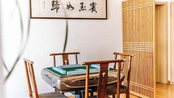 A room with a tatami mat table, wooden chairs, a snooker table, and a shoji screen.