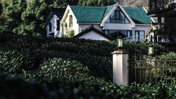 Um imóvel murado com um viveiro em primeiro plano e uma fileira de casas com telhados verdes ao fundo.