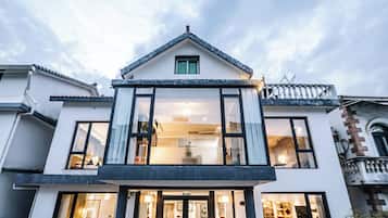 Ein modernes, zweistöckiges Gebäude mit einem zentralen Eingang, großen Fenstern und einem Balkon.