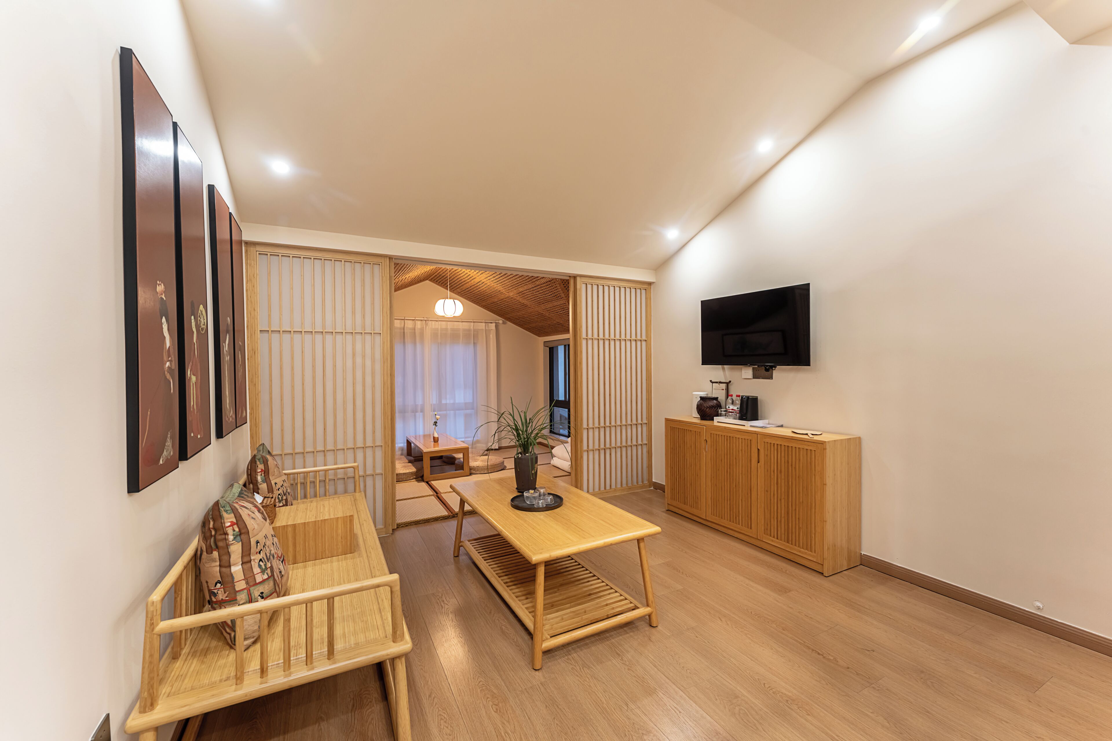 Un espacio habitable moderno con comedor, televisor montado en la pared y un mueble de madera.