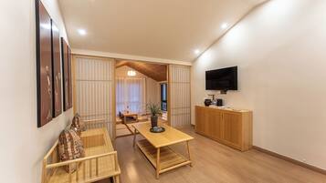 Un espacio habitable moderno con comedor, televisor montado en la pared y un mueble de madera.