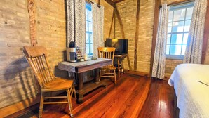 Una habitación acogedora con suelo de madera, una cama, una mesa con sillas, un televisor y cortinas estampadas.