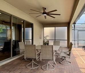 An outdoor patio with wicker furniture, a ceiling fan, and a view through glass doors. - Luxury 8BR 6BA Villa with Heated Pool, Spa, Themed Rooms, and EV Charger (Kissimmee)