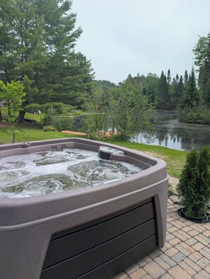 A hot tub with a view of a lake and trees. - Waterfront Cabin | Spa | Fireplaces | Gazebo (Bowman)