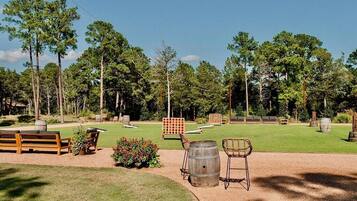 A well-maintained outdoor area with a wooden bench, a barrel chair, and a small garden.