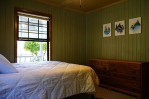 A bedroom with a bed, a dresser, and a window with blinds.