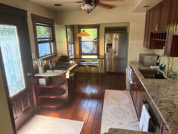 A kitchen with a central island, bar stools, a refrigerator, and a window with a view.