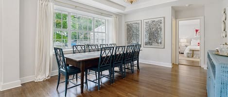 A dining room with a large table and chairs, a chandelier, and artwork on the walls.