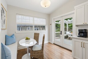 Una habitación con una mesa de comedor, sillas, una cafetera y vistas a una terraza exterior a través de un ventanal.