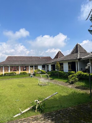 A traditional building with a tiled roof, a grassy courtyard, and a swing set.