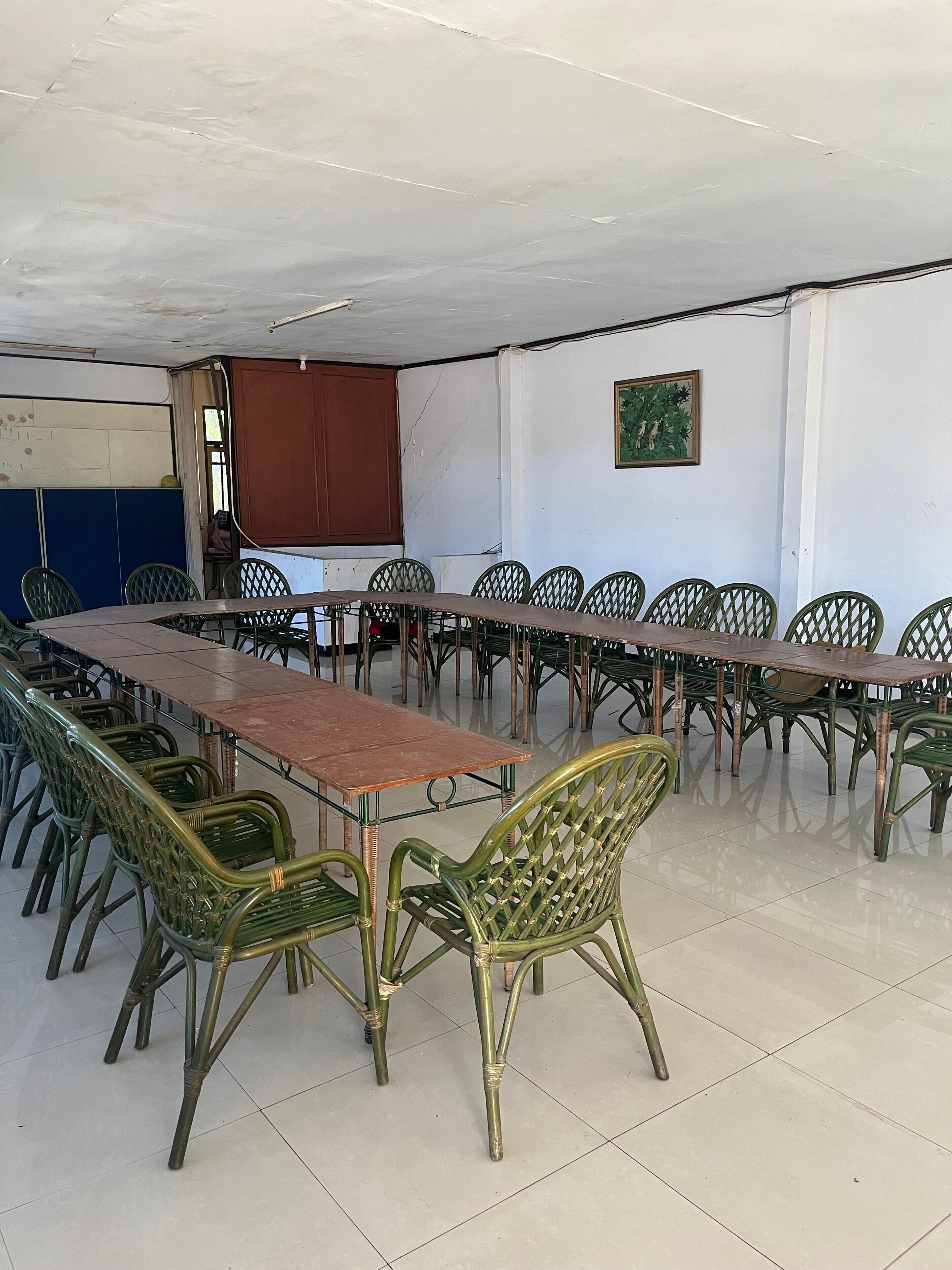 A conference room with a long table and multiple chairs, a whiteboard, and a painting on the wall.