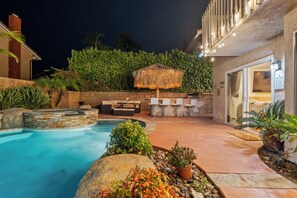 A pool area with a hot tub, outdoor seating, and a covered umbrella.