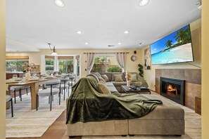 A living room with a sofa, a fireplace, a television, and a dining area with a table and chairs. - Entire Private House with 4 BR, 3.5 Bath, Garage, Pool, Hot Tub, 2500 sqft House (El Cajon)