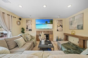 A living room with a large flat-screen TV, a fireplace, and a comfortable seating area.