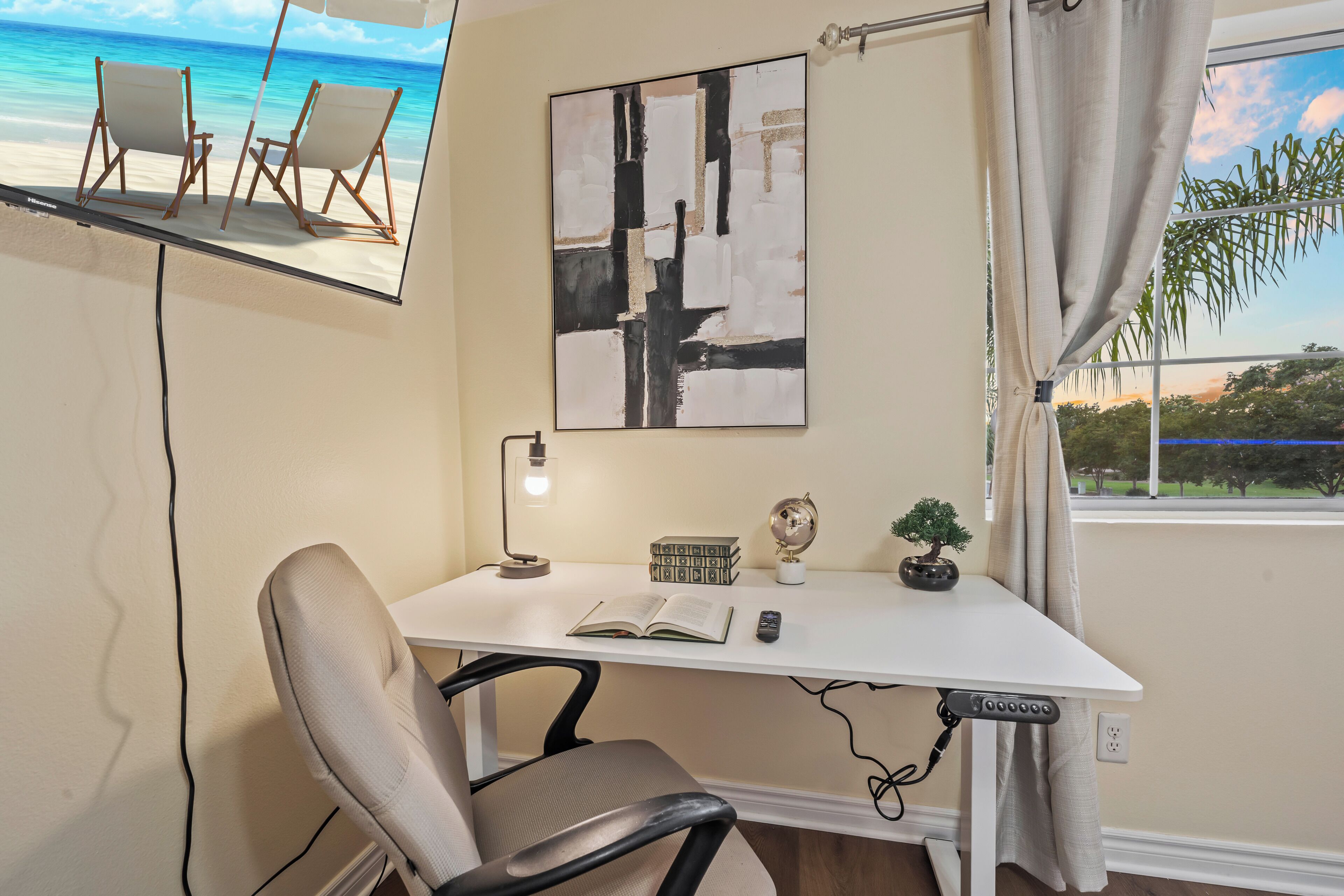 Une pièce comprenant un bureau, une chaise et une grande fenêtre donnant sur la plage.