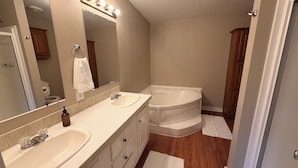 A bathroom with two sinks, a large mirror, and a bathtub.