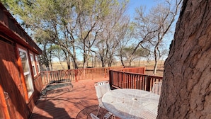 A wooden deck with a metal table and chairs, surrounded by trees.