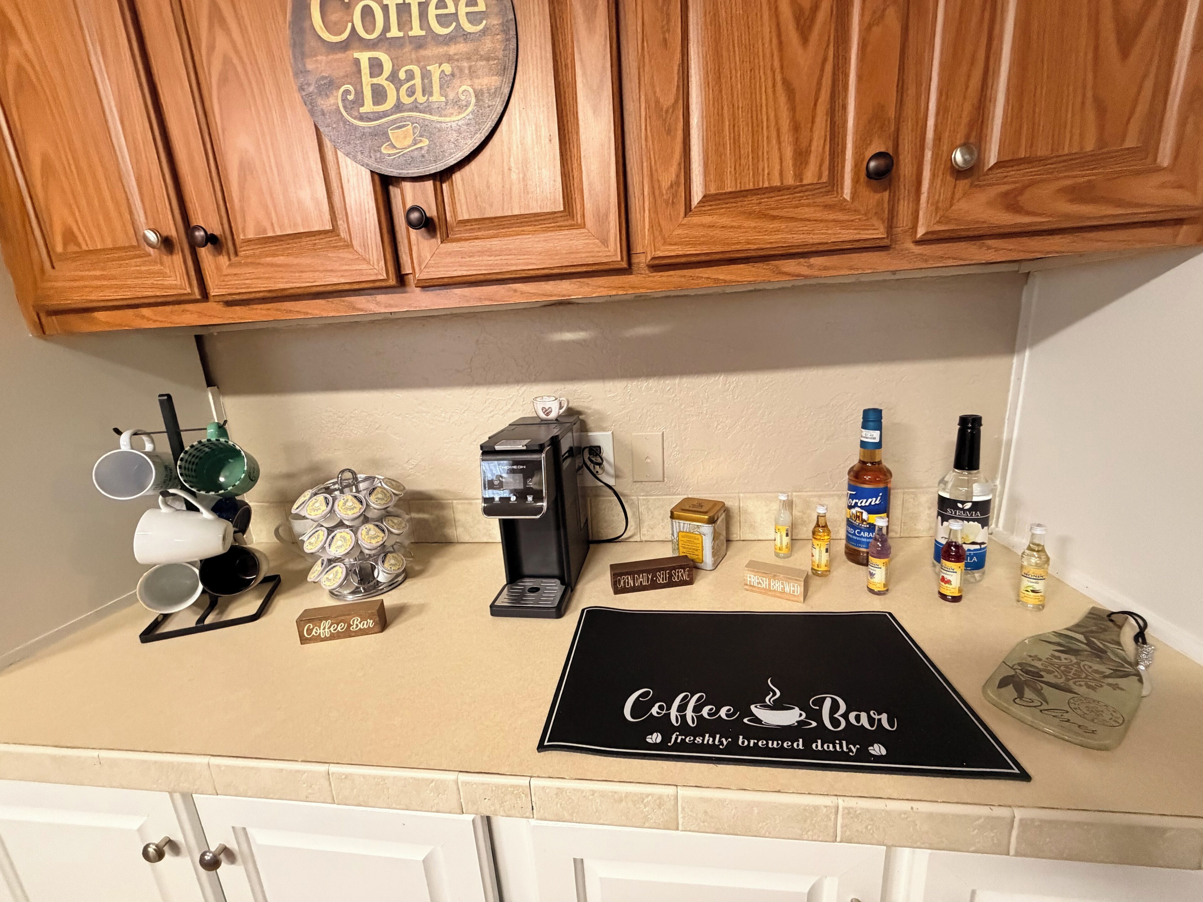 A kitchen counter with a coffee machine, coffee cups, a coffee grinder, and various coffee-related items.