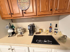 A kitchen counter with a coffee machine, coffee cups, a coffee grinder, and various coffee-related items.