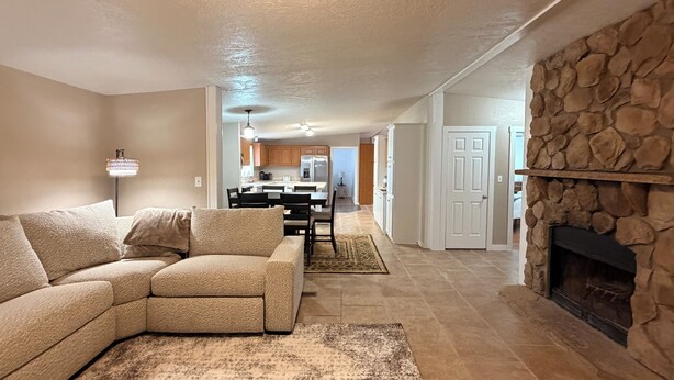 A living room with a sectional sofa, a fireplace, and a kitchen in the background.
