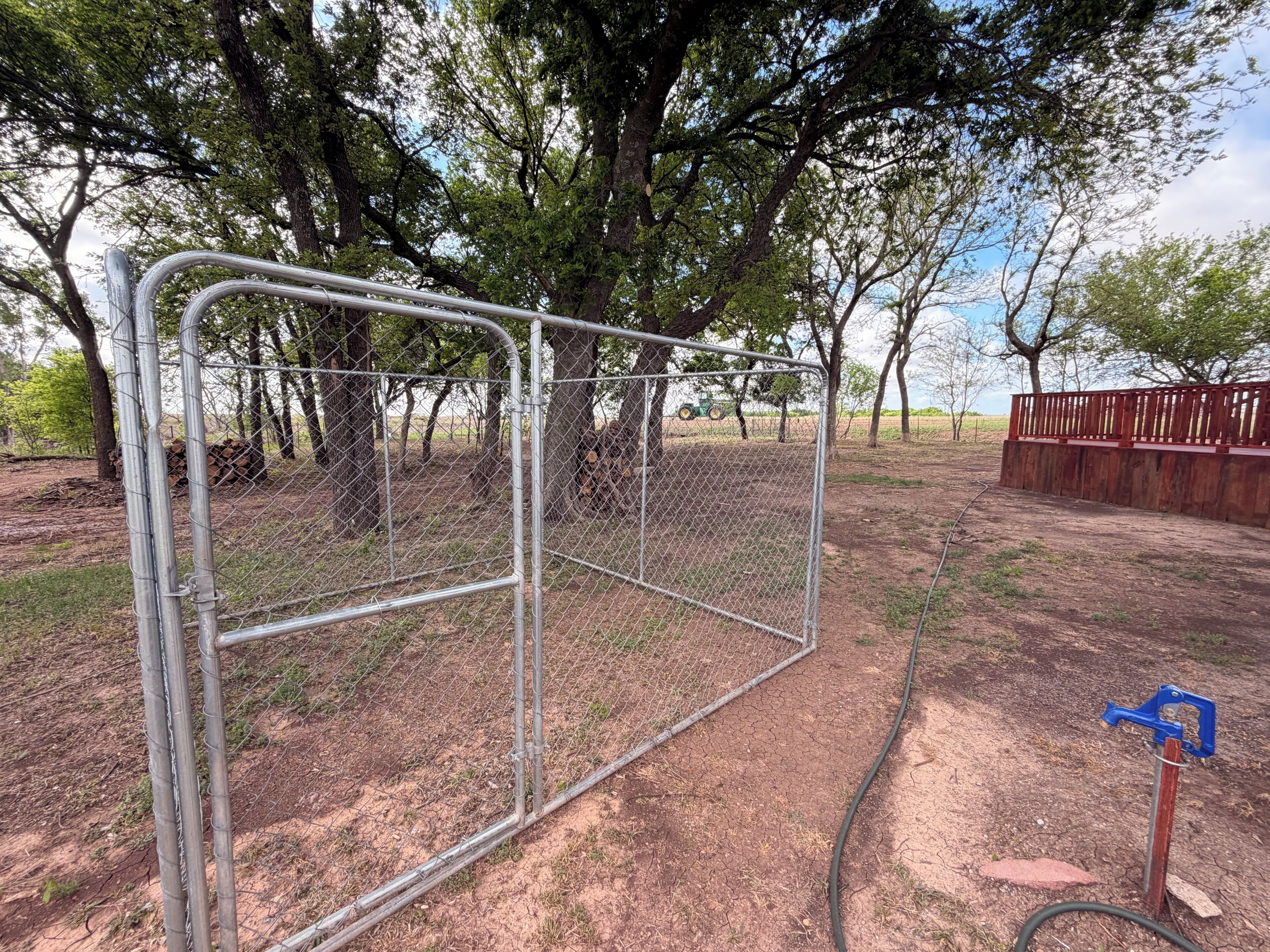 A fenced area with trees and a red wooden structure.