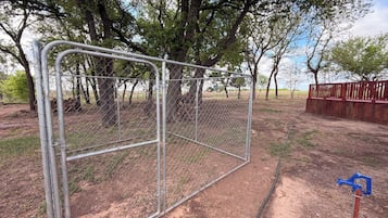 A fenced area with trees and a red wooden structure.