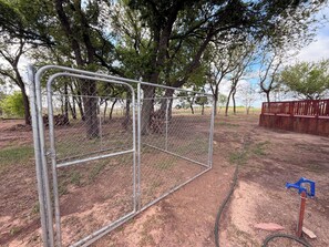 A fenced area with trees and a red wooden structure.