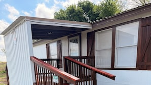 A small, single-story building with a wooden staircase leading to a covered entrance.