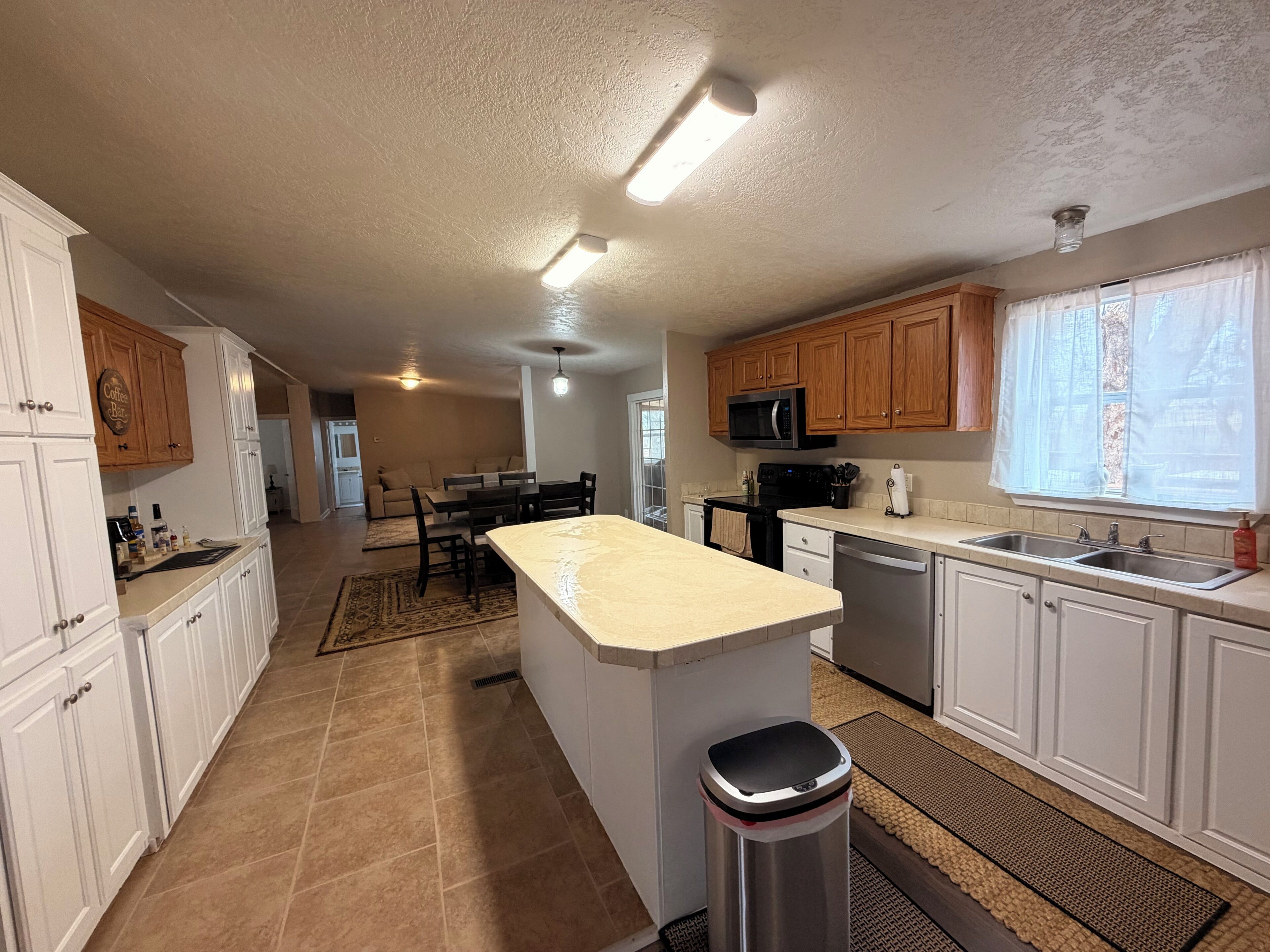 A kitchen with white cabinets, a central island, a microwave, and a sink.