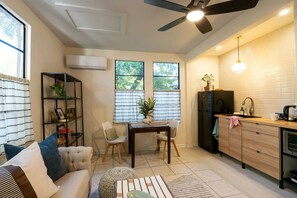 A compact living space with a kitchenette, a dining area, and a seating area with a sofa and chairs. - El Apartemento | Cozy 1BR Cottage with Private Deck Near Ybor City, Armature Works & Downtown Tampa (Tampa)