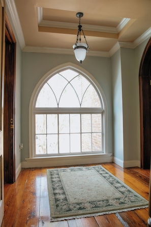 A room with wooden flooring, a large arched window, and a hanging light fixture. - French Quarter-Style Retreat, Private Pool, Theater, Wine Cellar & Game Room (Lafayette)