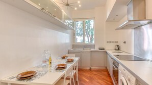 A compact kitchen with a dining area, a window with a view of trees, and a modern stainless steel range hood. - Gorgeous apartment in Genova with WiFi (Genova)