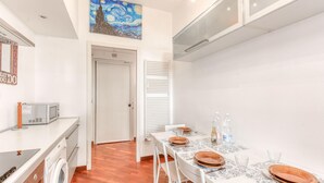 A modern kitchen with a dining area, a microwave, a washing machine, and a painting on the wall. - Gorgeous apartment in Genova with WiFi (Genova)