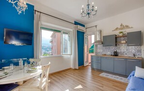 Eine moderne Küche mit Essbereich, einem an der Wand montierten Fernseher und Blick auf die Stadt durch das Fenster.