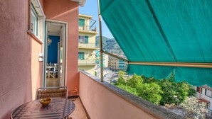 Ein Balkon mit Tisch und Stühlen, Blick auf die Stadtlandschaft und ein grünes Markisen.