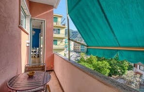 A balcony with a table and chairs, a view of the cityscape, and a green awning. - 1 bedroom amazing apartment in Rapallo (Rapallo)