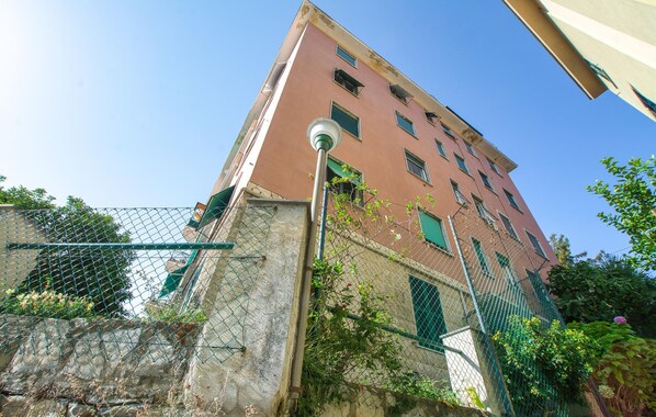 Un immeuble à plusieurs étages, avec une clôture en treillis métallique devant.