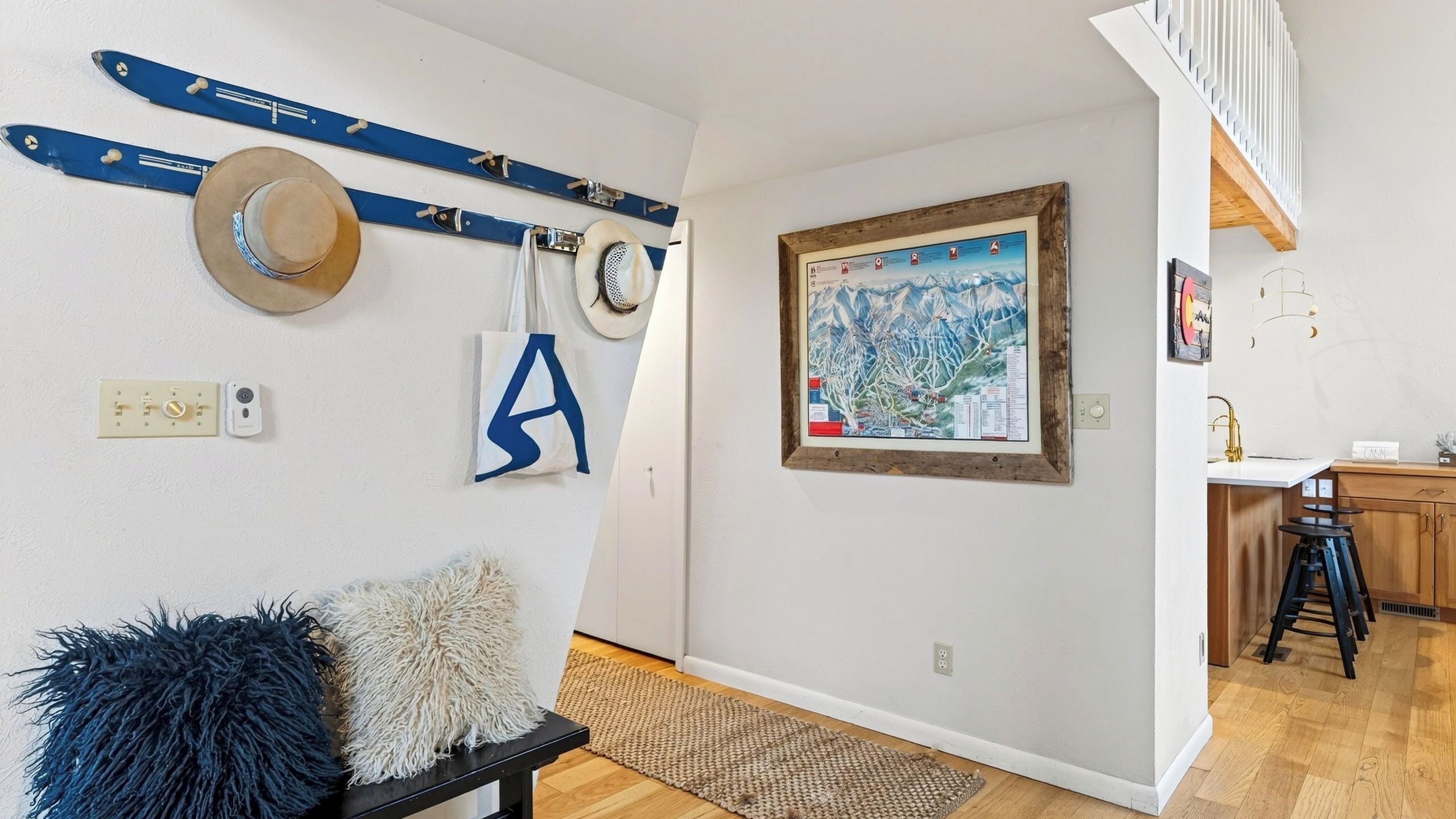 A room with a wooden bench, a map on the wall, and a staircase leading to another level.