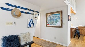 Une pièce avec un banc en bois, une carte accrochée au mur et un escalier menant à un autre niveau.