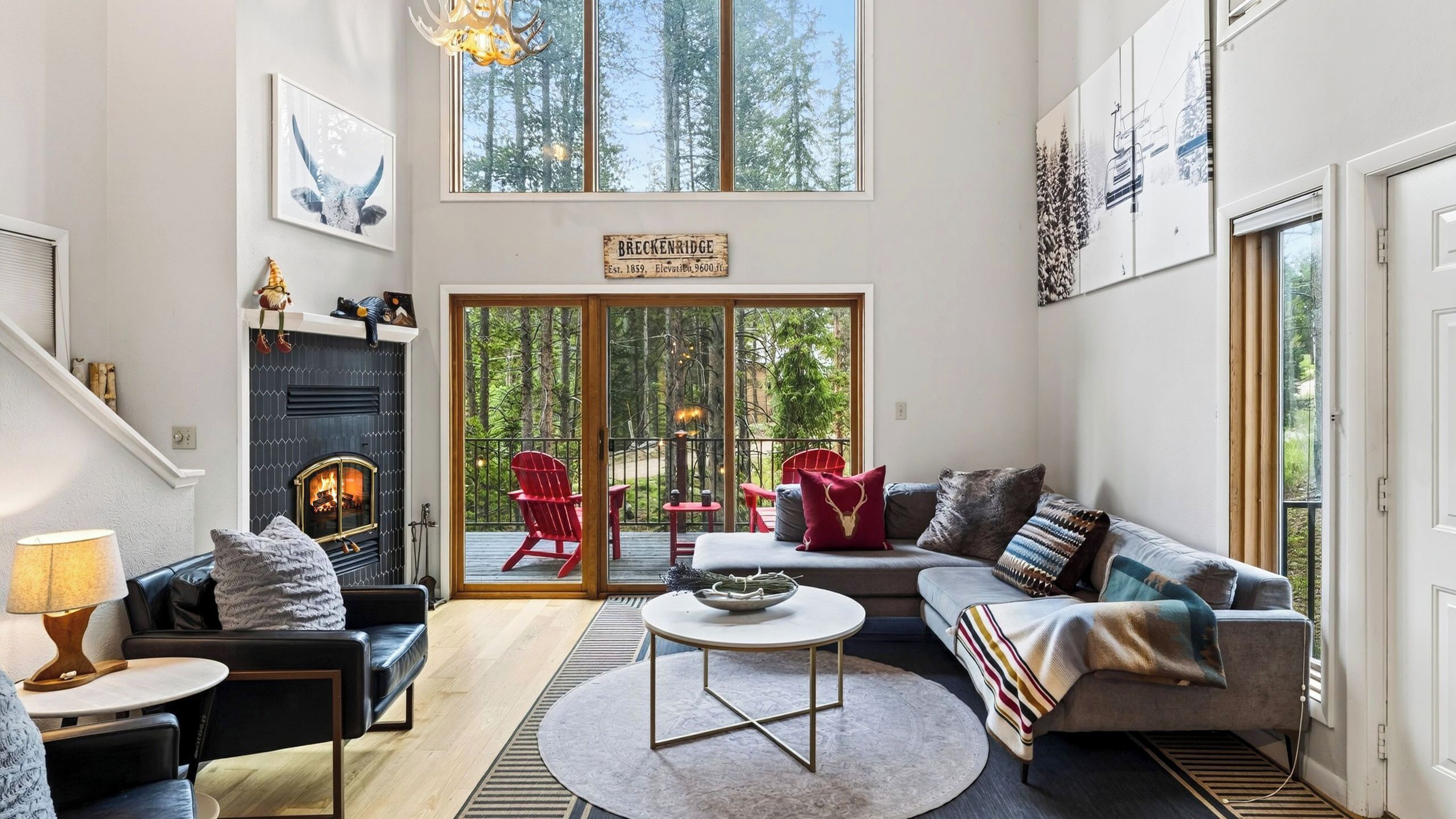 Amplia sala de estar con chimenea, un conjunto de sofás, una mesa de centro y vistas a una terraza con mobiliario exterior.