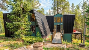 Une cabane moderne, dotée d’un toit en pente, entourée d’une forêt.